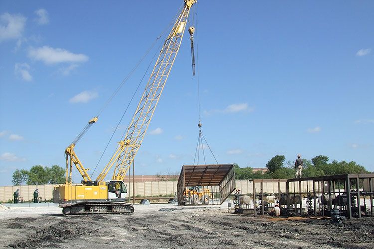 Protective wellhead enclosure being placed by crane